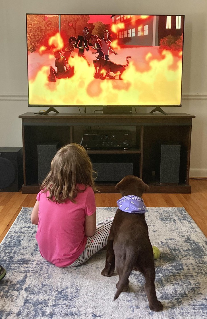 Момиче гледа анимации с кучето си